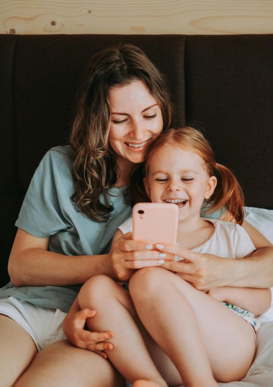 Mutter und Tochter schauen lachend gemeinsam aufs Handy